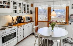 a kitchen with white cabinets and a table with flowers on it at Beautiful Home In Hllingsj With Lake View in Hällingsjö