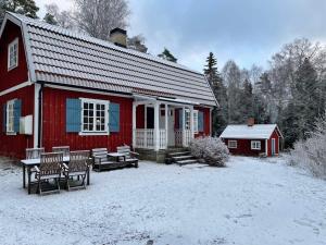 Holiday home JÄRNA II في Järna: حظيرة حمراء مع مقاعد في الثلج