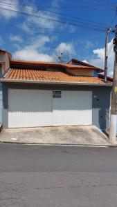 a white building with a red roof on a street at Quarto Aconchegante Completo in Cruzeiro