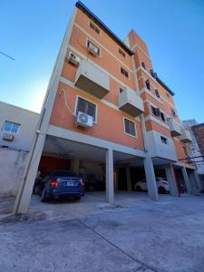 un grande edificio con un'auto parcheggiata in un parcheggio di Apart Checatu I a Corrientes