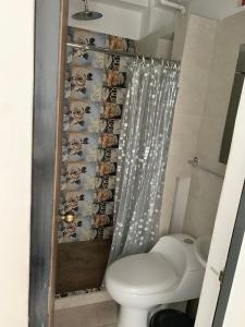 a bathroom with a toilet and a shower curtain at La Curva Apartamentos in Cali