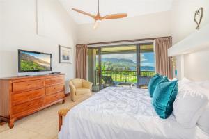 Schlafzimmer mit einem Bett, einem TV und einem Balkon in der Unterkunft Hanalei Bay Resort 7307 in Princeville