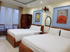 a hotel room with two beds and a mirror at Khách sạn Anh Đào in Tam Ðảo
