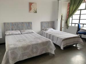 a bedroom with two beds and a chair and windows at La Curva Apartamentos in Cali