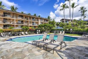 ein Pool mit Stühlen und ein Hotel in der Unterkunft Kona Makai 2103 in Kailua-Kona