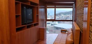 Una sala de estar con televisión y una gran ventana. en Modernos Departamentos - Lake Titicaca Puno, en Puno