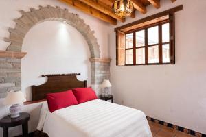 1 dormitorio con cama blanca y almohadas rojas en La Casa Veintidós en Guanajuato