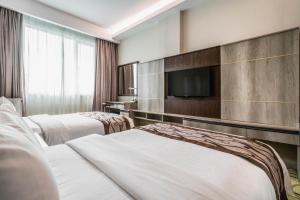 a hotel room with two beds and a flat screen tv at Ano Hotel in Miri