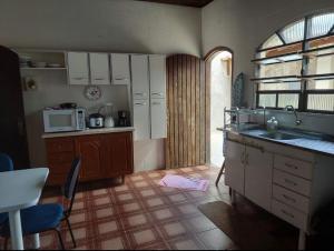 a kitchen with a sink and a microwave at Casa Guarujá c/ piscina grande in Guarujá