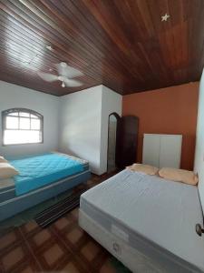 a bedroom with two beds and a wooden ceiling at Casa Guarujá c/ piscina grande in Guarujá