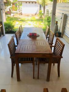 une table en bois entourée de chaises sur la terrasse. dans l'établissement Rumah DOLE, à Gili Air