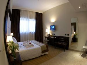 米兰iH Hotels Milano Watt 13的酒店客房带一张床、一张书桌和一面镜子