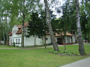 une maison blanche avec des arbres devant elle dans l'établissement Hotel Restauracja Cztery Pory Roku, à Orneta