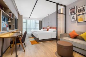 深セン市にあるHome2 Suites by Hilton Shenzhen Nanshan Science & Technology Parkのベッドとテーブルが備わるホテルルームです。