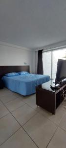 a bedroom with a bed and a desk with a television at Varandas - Apartamentos in Natal