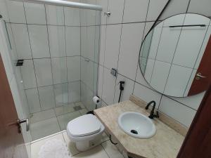 a bathroom with a toilet and a sink and a mirror at Casa Executiva Orla Morena in Campo Grande