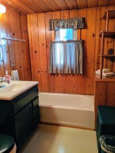 ein Bad mit einem Waschbecken, einer Badewanne und einem Fenster in der Unterkunft Cabin #5 in Strawberry