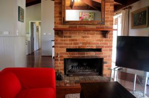 a living room with a red couch and a fireplace at Yackandandah farm homestead in Yackandandah