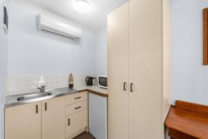 a kitchen with white cabinets and a sink at Bent Street Motor Inn in Grafton
