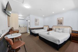 a hotel room with two beds and a table at Bent Street Motor Inn in Grafton