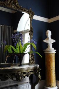 un espejo y un jarrón con flores moradas en una mesa en Flemings Country House en Cork