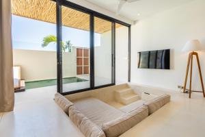 ein Wohnzimmer mit einem Sofa und großen Fenstern in der Unterkunft Sore Apartment by Hombali in Canggu