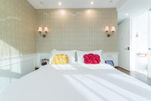 Duas almofadas coloridas sentadas numa cama branca em Tung Nam Lou Art Hotel em Hong Kong