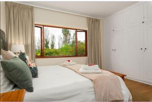 a bedroom with a large white bed with a window at Valley Heights Guest House and B & B in Cape Town