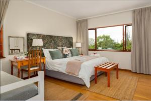 1 dormitorio con 1 cama grande, escritorio y ventana en Valley Heights Guest House and B & B, en Ciudad del Cabo