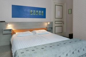 een slaapkamer met een groot wit bed met 2 kussens bij Hotel Beukenhorst in Wittem