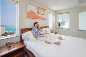 a man and a woman sitting on a bed at SOCO Hotel by THG in Danang