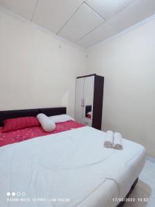 ein Schlafzimmer mit einem großen weißen Bett mit zwei Kissen in der Unterkunft Kost Griya Asri by ecommerceloka in Jakarta