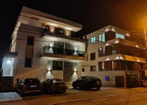 dos autos estacionados frente a un edificio por la noche en SarmiHouse en Cluj-Napoca
