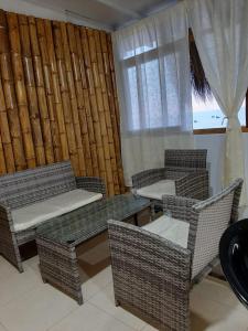 a living room with wicker chairs and tables and a window at Bungalows Bella Vista in Zorritos