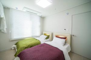 twee bedden in een kamer met een raam bij Sai in Daejeon