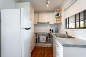 エメラルド・ビーチにあるSurfs Up! Oceanfront Home Sleeps 6 steps from the sandのシンクと冷蔵庫を備えた白いキッチン