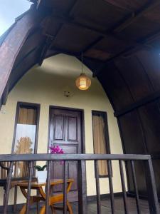 a porch with a table and chairs and a door at Pondok Ganesha Bali in Gitgit