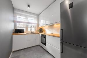 a kitchen with white cabinets and a refrigerator at Golden Sands in Łódź