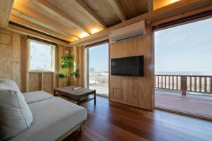 sala de estar con sofá y TV de pantalla plana en Okhotsk Ocean Villa AL MARE mombetsu, en Mombetsu