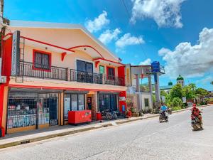 two people riding motorcycles down a street in front of a building at Victoria's Inn in General Luna