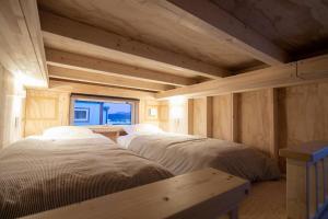 Habitación de madera con 2 camas y ventana en Okhotsk Ocean Villa AL MARE mombetsu en Mombetsu
