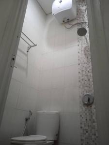 een witte badkamer met een toilet en een douche bij MURAI Guesthouse Bali in Denpasar