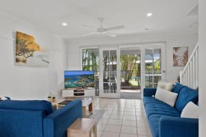 ein Wohnzimmer mit blauen Sofas und einem TV in der Unterkunft Coco Bay Resort in Noosaville