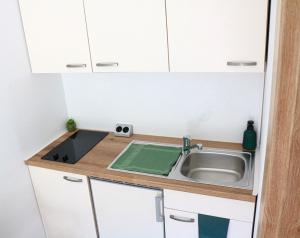 Elle comprend une petite cuisine avec un évier et des placards blancs. dans l'établissement Haus M&M, à Brixen im Thale
