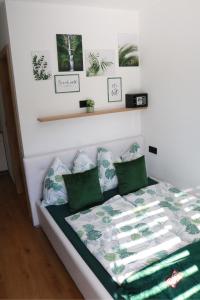 - un lit avec des draps et des oreillers verts et blancs dans l'établissement Haus M&M, à Brixen im Thale