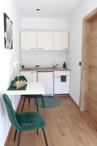 une cuisine avec une table et une chaise verte dans l'établissement Haus M&M, à Brixen im Thale