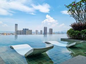 a pool with two white chairs in the water with a city at Lavish Beacon Executive Suites by Bin Dao Wu Homestay Penang in George Town
