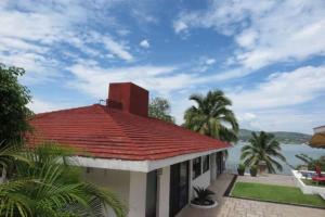 een huis met een rood dak en een waterlichaam bij Casa en Teques con alberca, vista y acceso al lago in Tequesquitengo