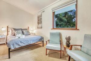 a bedroom with a bed and two chairs and a window at Cedar Cottage Unit 5 in Bright +23 photos