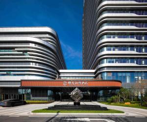 a large office building with a statue in front of it at Sunstone Plaza Hotel in Binzhou